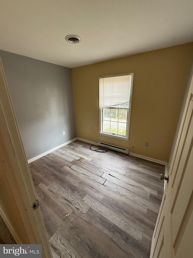 spare room with light wood-type flooring and baseboard heating