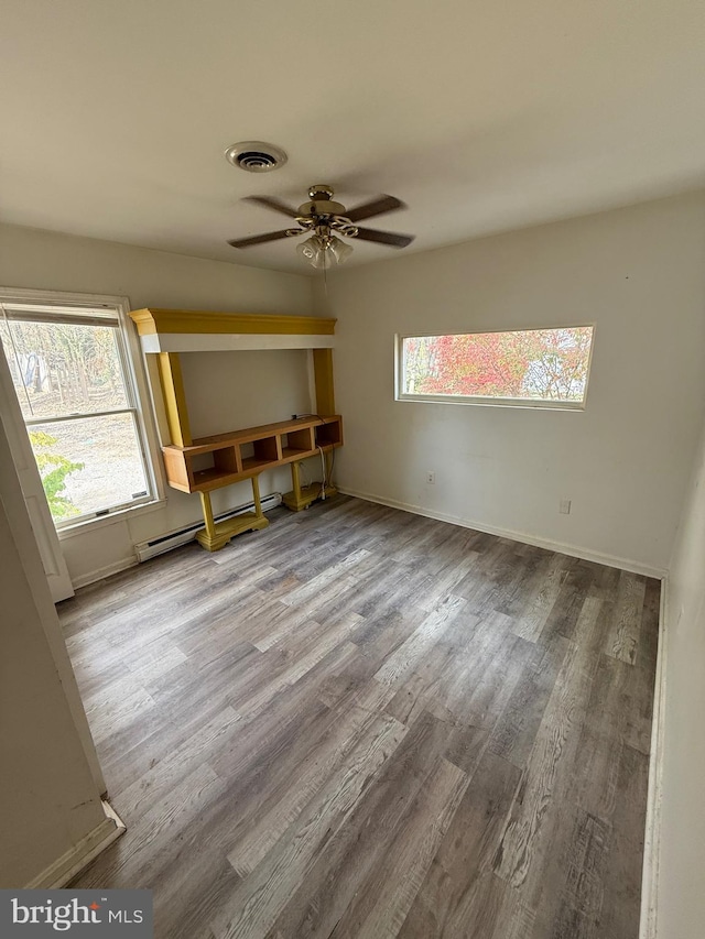 spare room featuring a wealth of natural light, ceiling fan, hardwood / wood-style flooring, and a baseboard heating unit