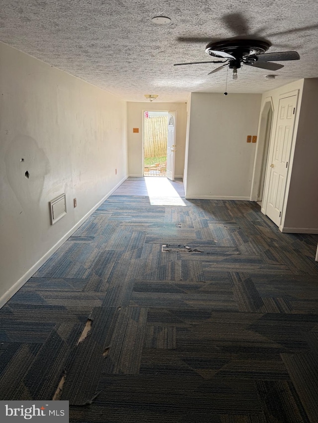 carpeted empty room with ceiling fan and a textured ceiling