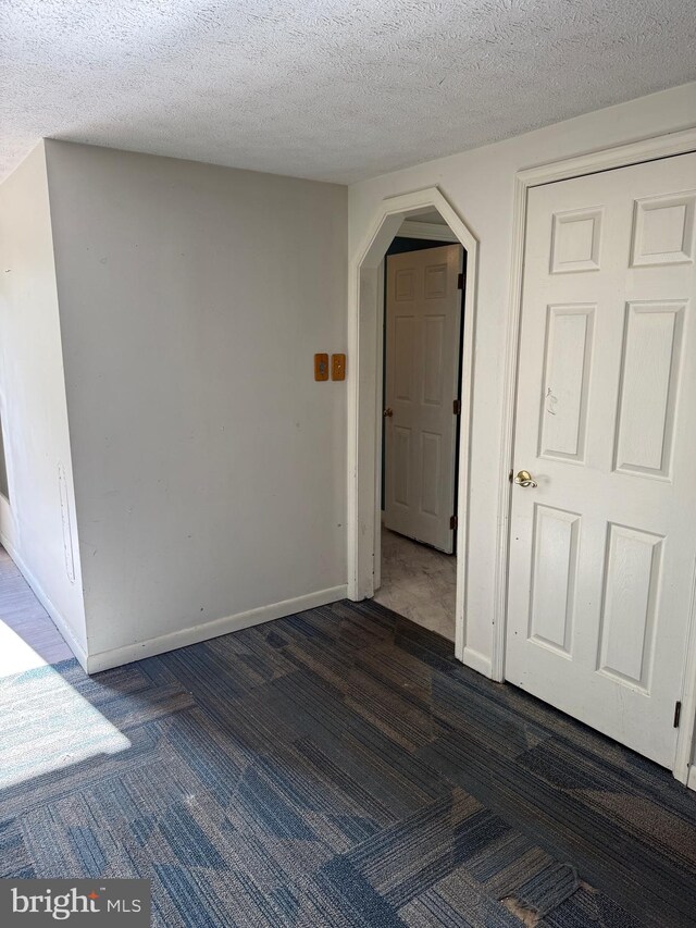 carpeted empty room featuring a textured ceiling