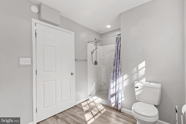 bathroom with curtained shower, wood-type flooring, and toilet