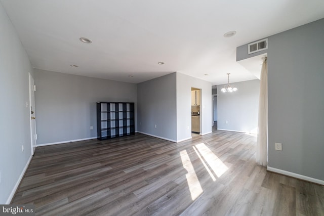 empty room with hardwood / wood-style flooring and a notable chandelier