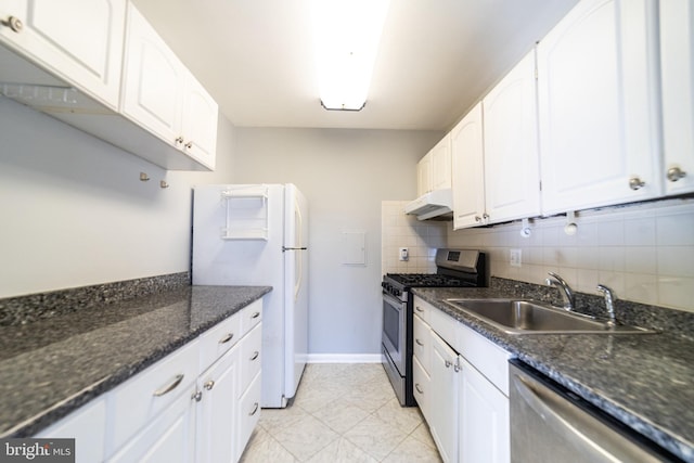 kitchen with appliances with stainless steel finishes, backsplash, dark stone counters, sink, and white cabinets