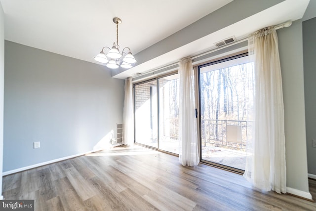 unfurnished room featuring light hardwood / wood-style floors and a notable chandelier