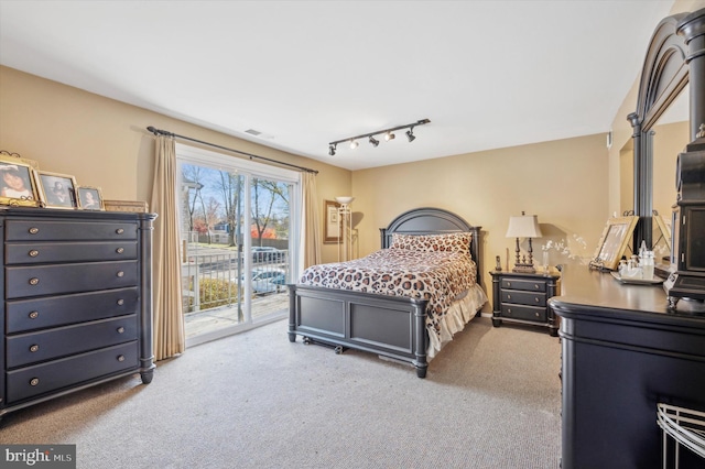 carpeted bedroom featuring rail lighting and access to outside