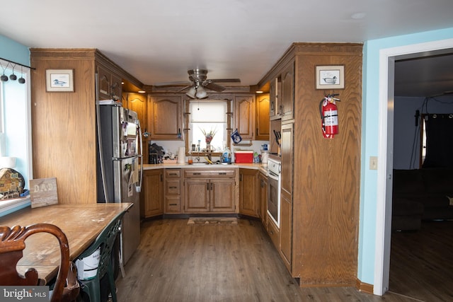 kitchen with stainless steel appliances, ceiling fan, dark wood-type flooring, and sink