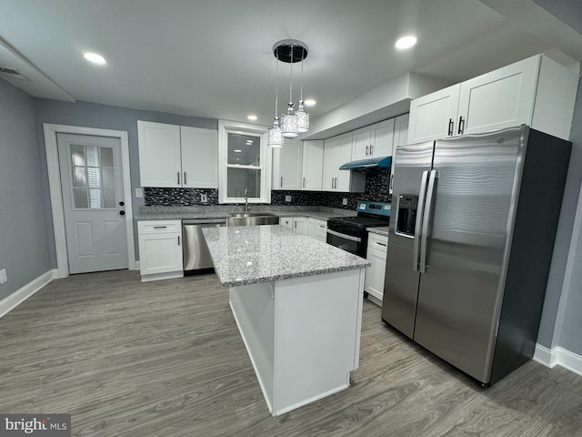 kitchen with decorative backsplash, stainless steel appliances, white cabinets, a center island, and hanging light fixtures