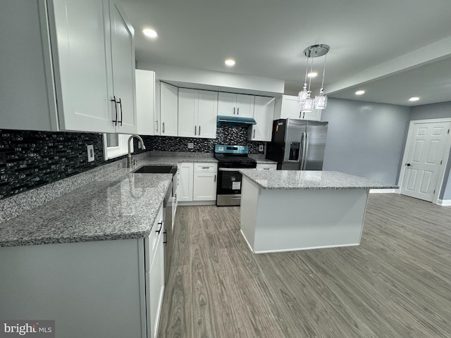 kitchen with pendant lighting, a center island, white cabinets, light hardwood / wood-style flooring, and appliances with stainless steel finishes