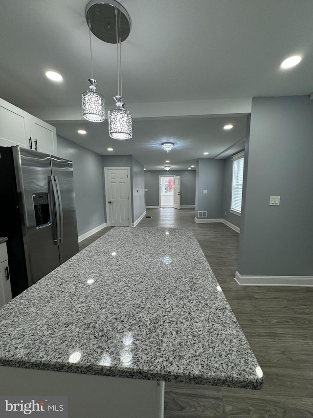 kitchen featuring stainless steel fridge with ice dispenser, light stone counters, dark hardwood / wood-style floors, pendant lighting, and white cabinets