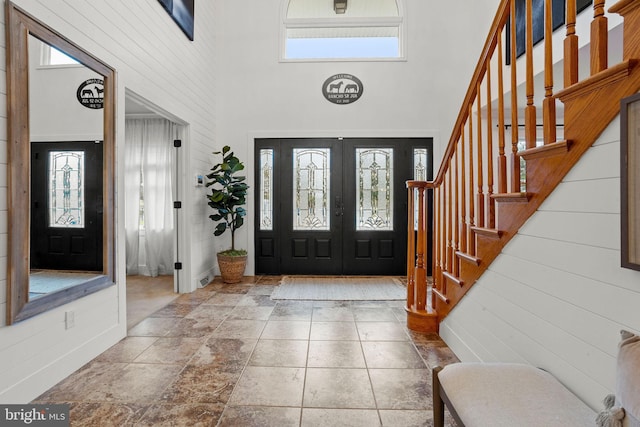 entryway with plenty of natural light, a towering ceiling, and french doors