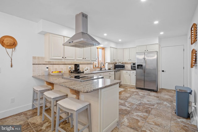 kitchen featuring appliances with stainless steel finishes, tasteful backsplash, light stone counters, white cabinetry, and island exhaust hood