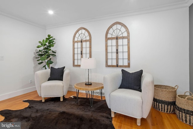 living area with wood-type flooring and ornamental molding