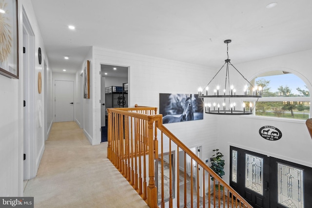 corridor with a chandelier and light colored carpet