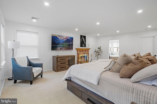 bedroom with a fireplace and light colored carpet