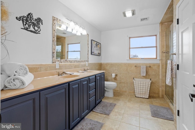 bathroom featuring tile patterned floors, plenty of natural light, toilet, and tile walls