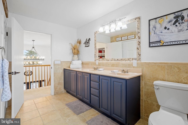 bathroom featuring a notable chandelier, tile patterned floors, toilet, vanity, and tile walls