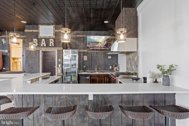 kitchen with kitchen peninsula, tasteful backsplash, stainless steel appliances, sink, and decorative light fixtures