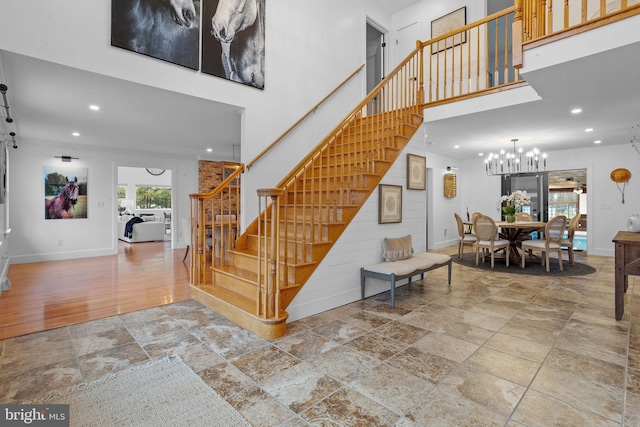 staircase featuring a towering ceiling, a notable chandelier, and hardwood / wood-style flooring