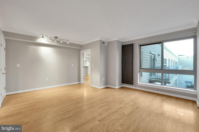 spare room featuring crown molding, light hardwood / wood-style flooring, and rail lighting