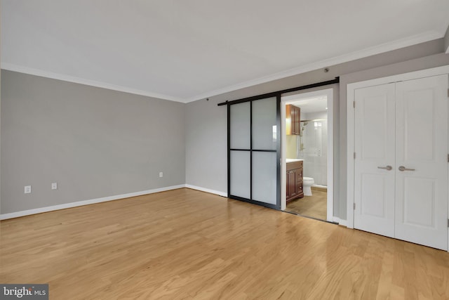 unfurnished bedroom with ensuite bath, crown molding, a closet, and light hardwood / wood-style floors