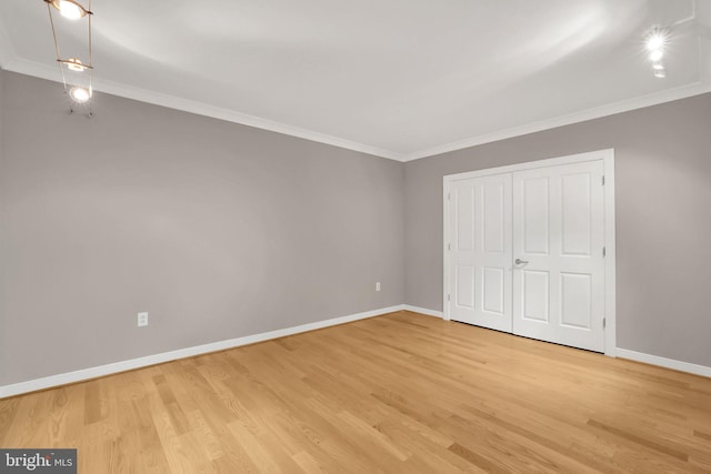 unfurnished bedroom with light hardwood / wood-style floors, crown molding, and a closet