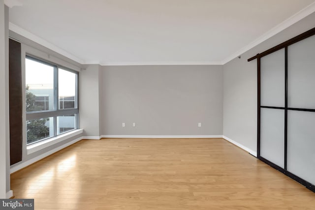 empty room featuring crown molding and light wood-type flooring