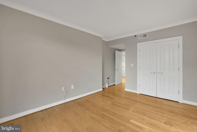 unfurnished bedroom featuring light wood-type flooring, a closet, and crown molding