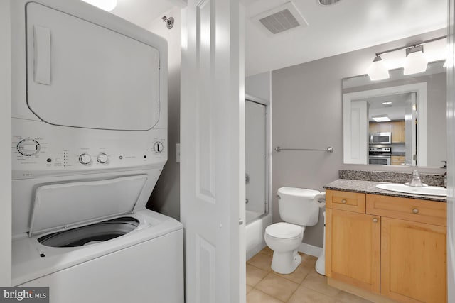 laundry area featuring stacked washer / drying machine, light tile patterned floors, and sink