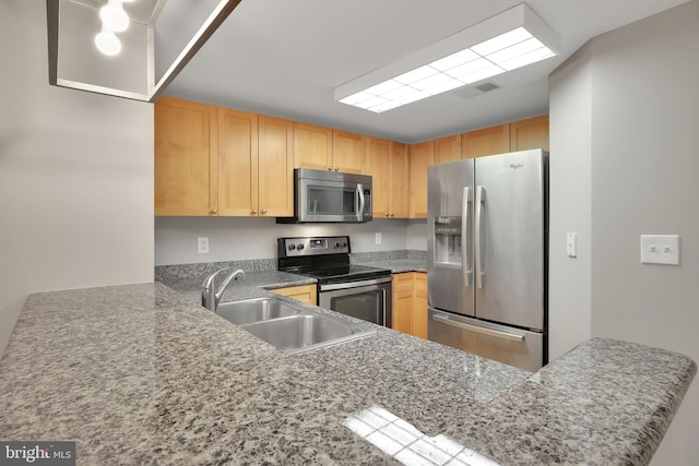 kitchen featuring kitchen peninsula, light brown cabinetry, stainless steel appliances, and sink