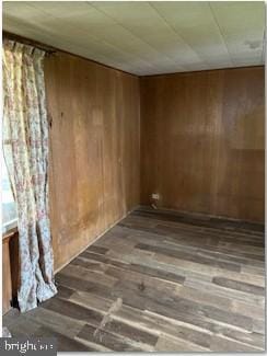 unfurnished room with hardwood / wood-style floors and wood walls