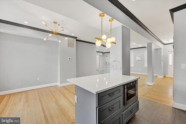 kitchen with crown molding, an inviting chandelier, hanging light fixtures, light wood-type flooring, and built in microwave