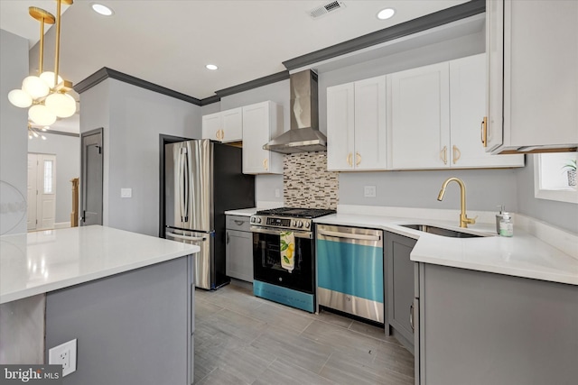 kitchen featuring sink, hanging light fixtures, appliances with stainless steel finishes, white cabinets, and wall chimney exhaust hood