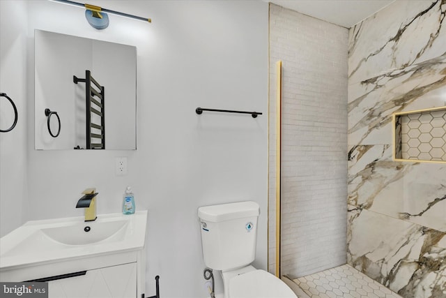 bathroom featuring toilet, tiled shower, and vanity