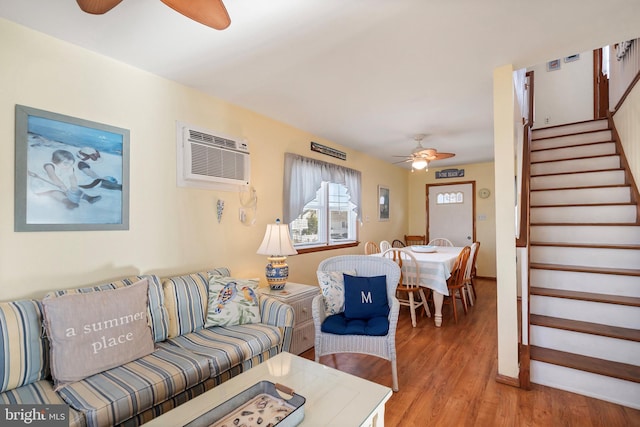 living room with a wall mounted AC, ceiling fan, and hardwood / wood-style flooring