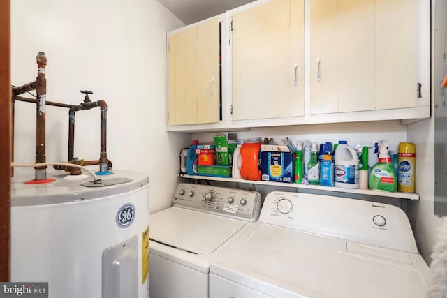 clothes washing area with cabinets, washing machine and dryer, and water heater