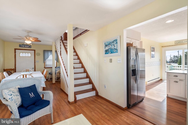 foyer with ceiling fan, a baseboard heating unit, and light hardwood / wood-style flooring