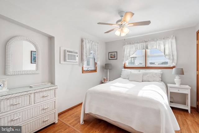 bedroom featuring light hardwood / wood-style flooring, ceiling fan, and an AC wall unit