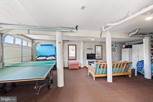 recreation room featuring plenty of natural light, a textured ceiling, and dark colored carpet