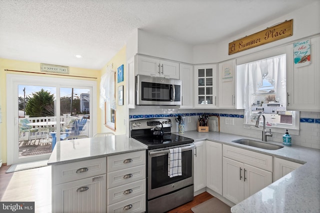 kitchen featuring white cabinetry, sink, light stone counters, and appliances with stainless steel finishes