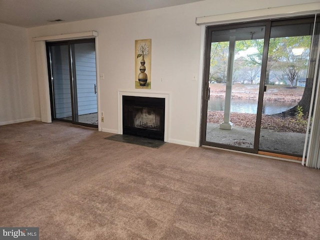 unfurnished living room with carpet floors and a water view