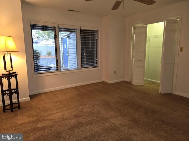 unfurnished bedroom with a closet, dark carpet, and ceiling fan