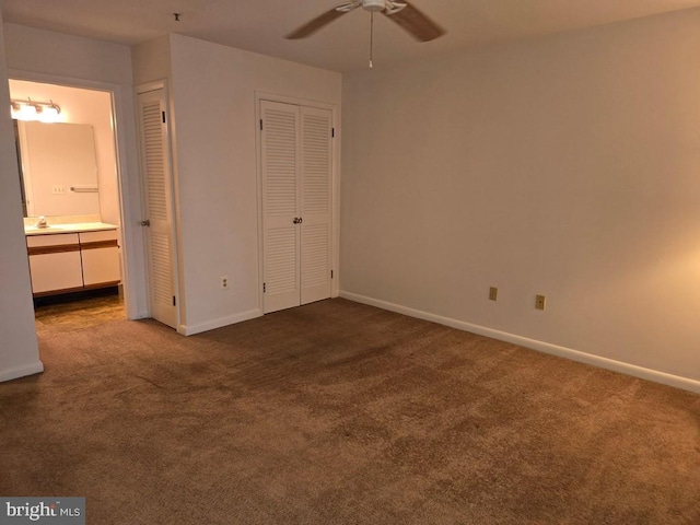 unfurnished bedroom with connected bathroom, dark carpet, ceiling fan, and sink