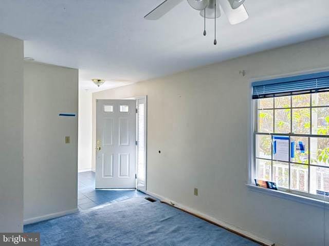 foyer entrance with ceiling fan and light carpet