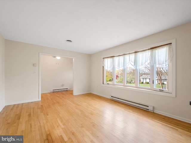 empty room with a baseboard heating unit, light hardwood / wood-style flooring, and a healthy amount of sunlight