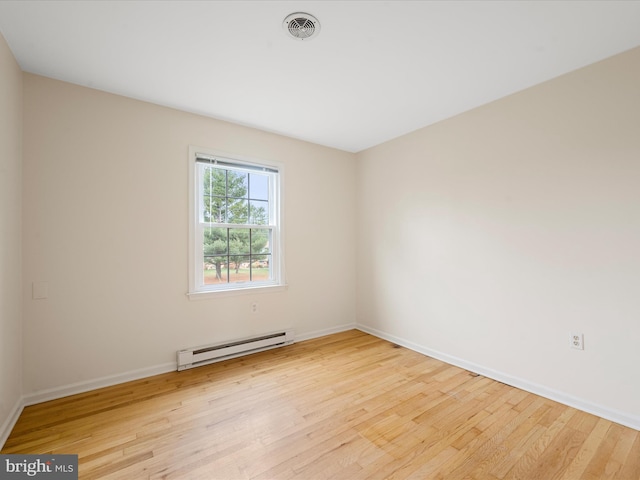 unfurnished room featuring a baseboard radiator and light hardwood / wood-style flooring