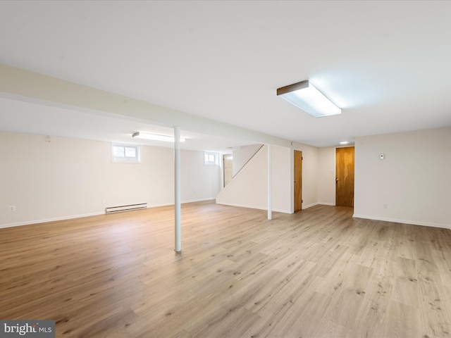 basement with a baseboard radiator and light hardwood / wood-style floors