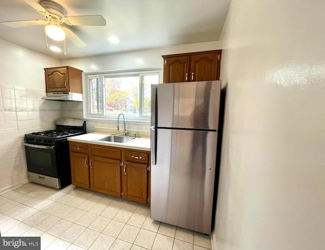 kitchen with ceiling fan, sink, light tile patterned floors, tile walls, and appliances with stainless steel finishes