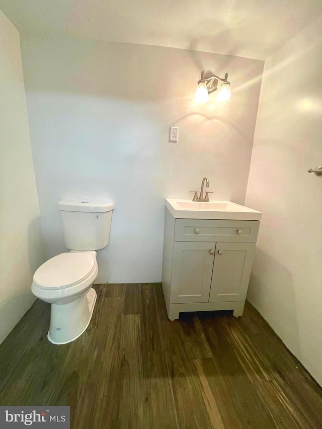 bathroom with toilet, vanity, and hardwood / wood-style flooring