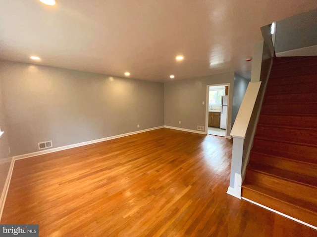 basement with hardwood / wood-style flooring and white refrigerator