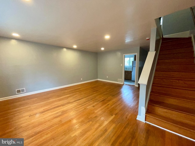 basement with hardwood / wood-style floors and white refrigerator